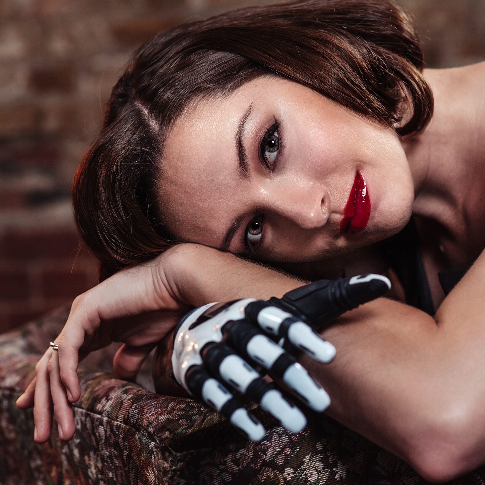 A woman poses with a white robotic hand.